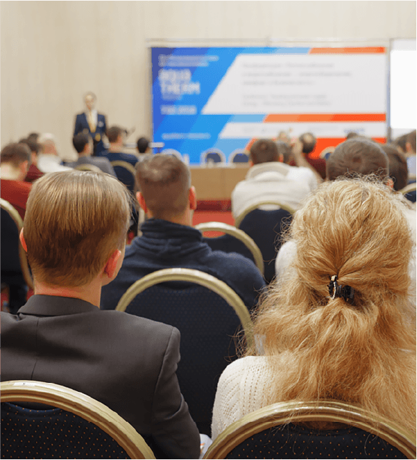 Image of a conference taking place in a meeting room with attendees and presenter.