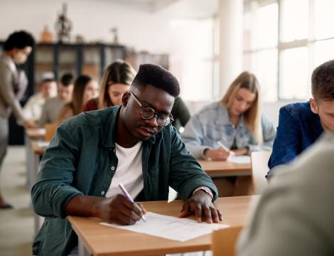 Boy Sitting at Desk Taking Notes
